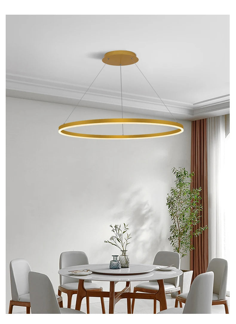 Nowoczesna lampa wisząca DAMIASMIL w kształcie złotego pierścienia nad stołem jadalnym w stylowym wnętrzu