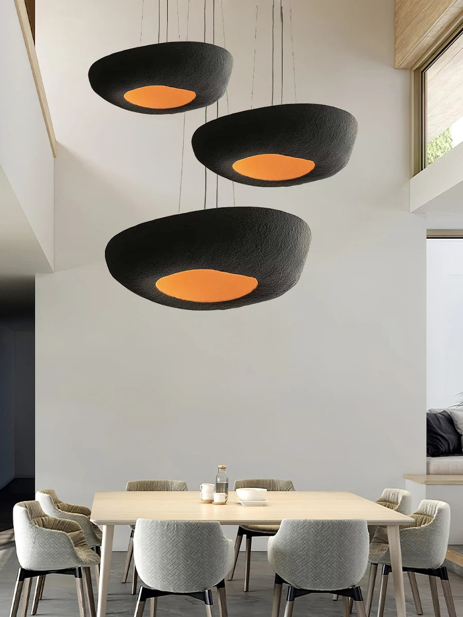 Czarna lampa wisząca Artpad z pomarańczowym wnętrzem nad stołem w jadalni