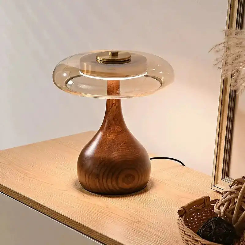 Elegancka lampa stołowa z drewnianą podstawą i szklanym kloszem na drewnianym blacie