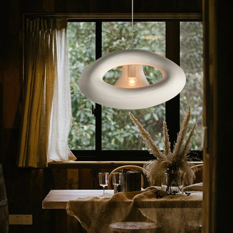 Lampy w stylu skandynawskim marki DRMIYA wisząca nad drewnianym stołem z dekoracją w naturalnym wnętrzu