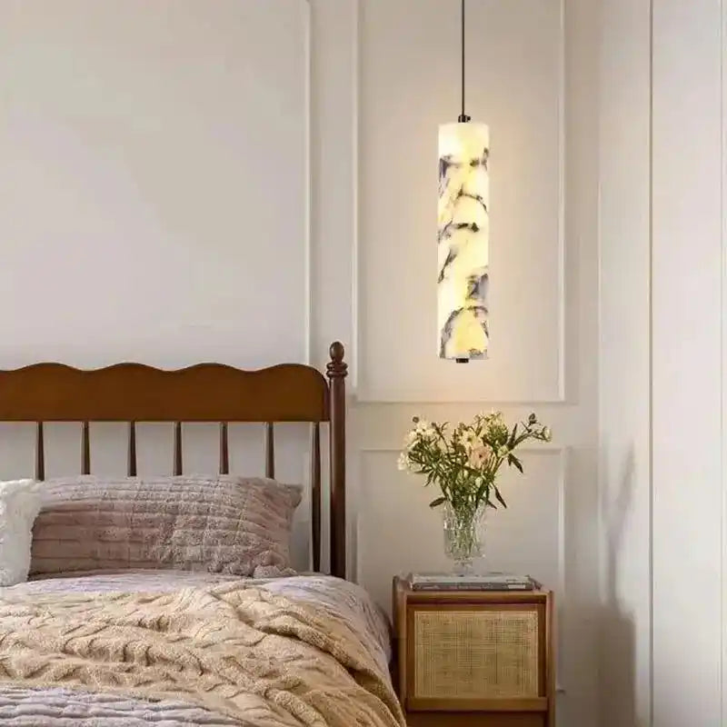 Nowoczesne lampy wiszące o cylindrycznym kształcie z marmurowym wzorem nad stolikiem nocnym