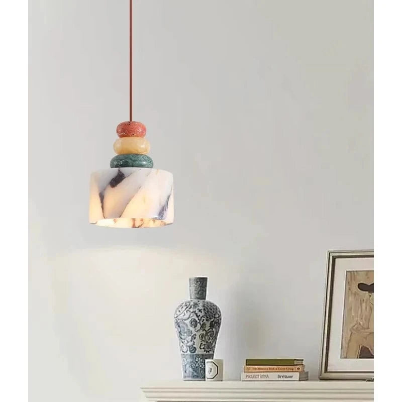 Nowoczesna marmurowa lampa wisząca z kolorowymi ozdobami nad stolikiem z dekoracjami
