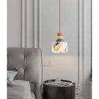 Marmurowa lampa wisząca z kolorowymi dekoracjami nad stolikiem nocnym przy łóżku w nowoczesnej sypialni