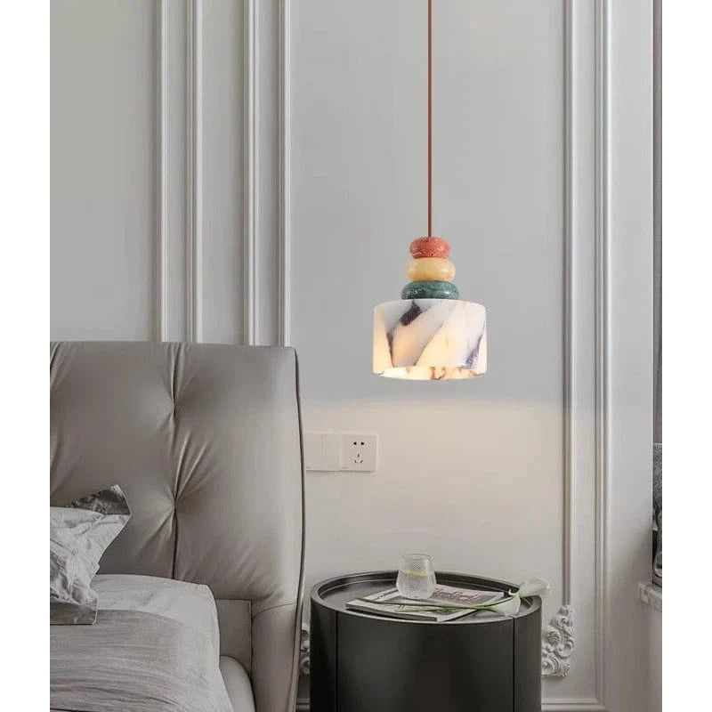 Marmurowa lampa wisząca z kolorowymi dekoracjami nad stolikiem nocnym przy łóżku w nowoczesnej sypialni