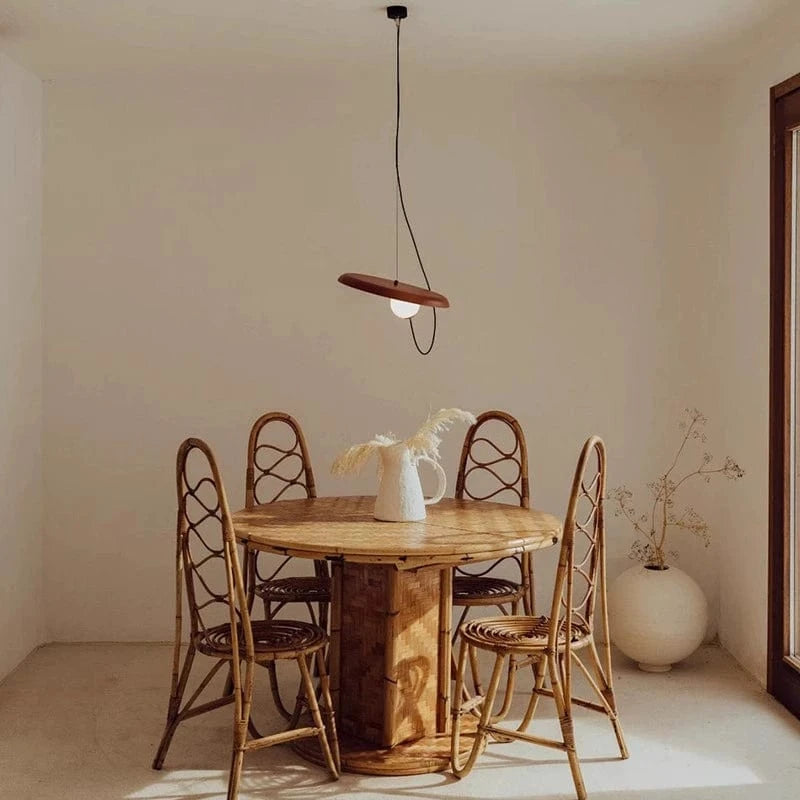 Minimalistyczna lampa wisząca z drewna nad okrągłym stołem z krzesłami w jadalni