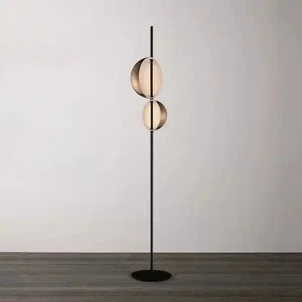 Nowoczesna lampa podłogowa z dwoma kulistymi kloszami na czarnej nodze na tle jasnej ściany