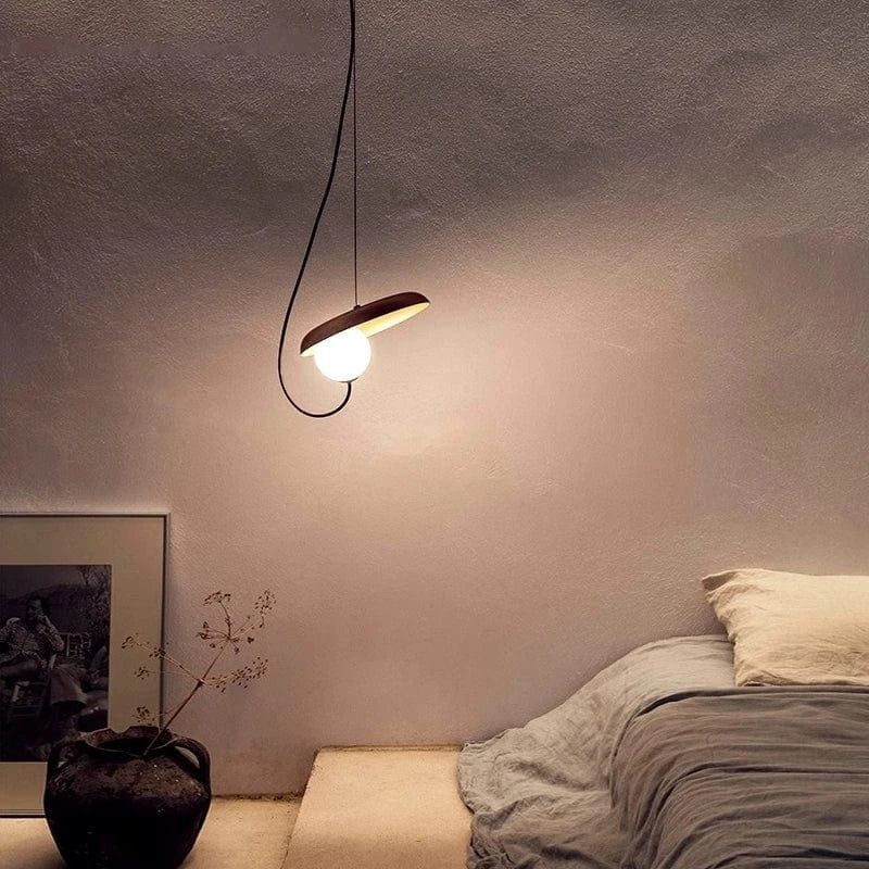Nowoczesna lampa wisząca z okrągłą żarówką w minimalistycznym wnętrzu sypialni