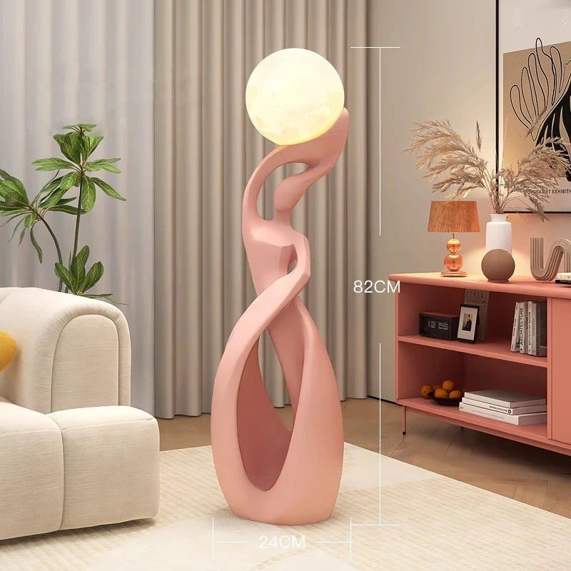 Rzeźbiarska lampa stojąca Gbbmade w różowym kolorze z kulistym źródłem światła do salonu