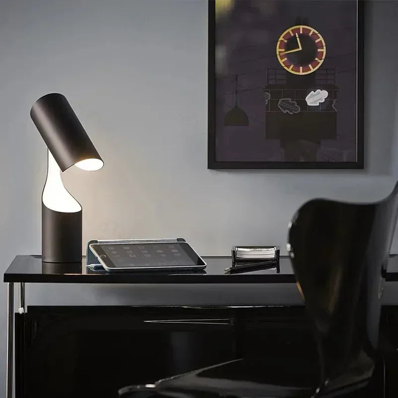 Stylowa lampa biurkowa o nowoczesnym designie na czarnym stole obok tabletu i czarnego krzesła