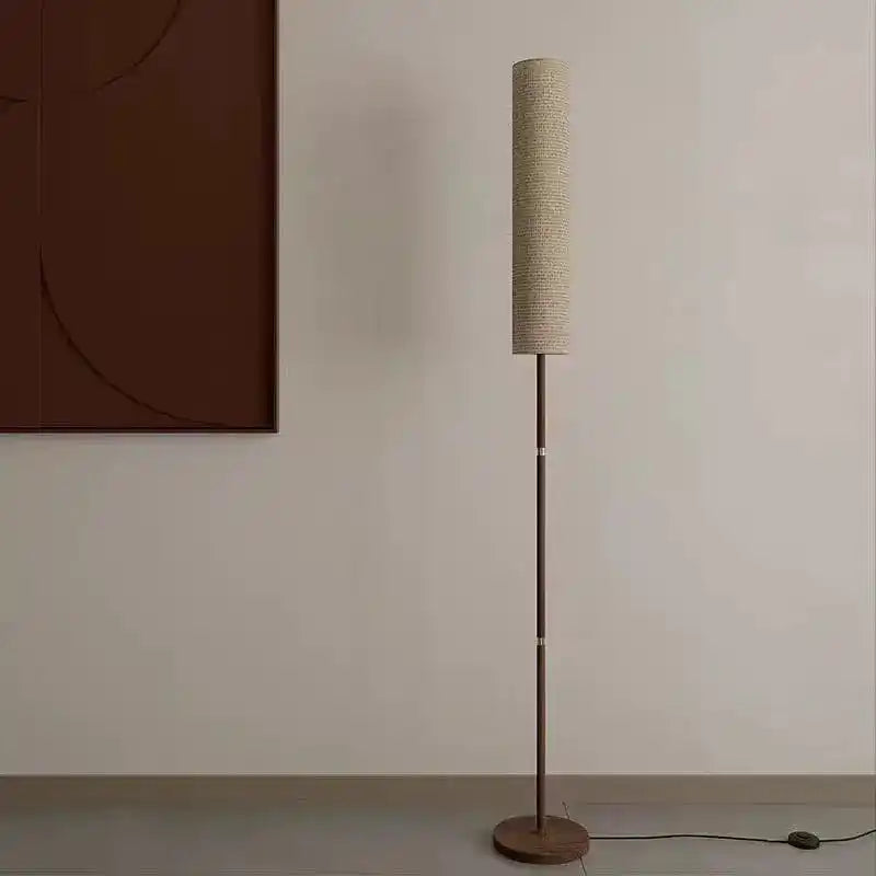 Stylowa lampa do wnętrz stojąca z wąskim cylindrycznym abażurem na metalowej podstawie