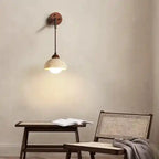Stylowa lampa wisząca nad stolikiem z otwartą książką i wiklinowym fotelem
