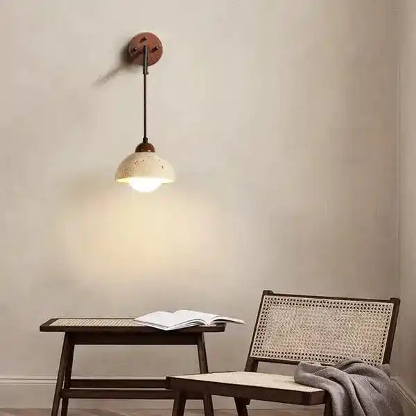 Stylowa lampa wisząca nad stolikiem z otwartą książką i wiklinowym fotelem