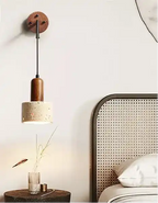 Stylowa lampa wisząca z drewnianym i betonowym kloszem nad stolikiem nocnym obok łóżka